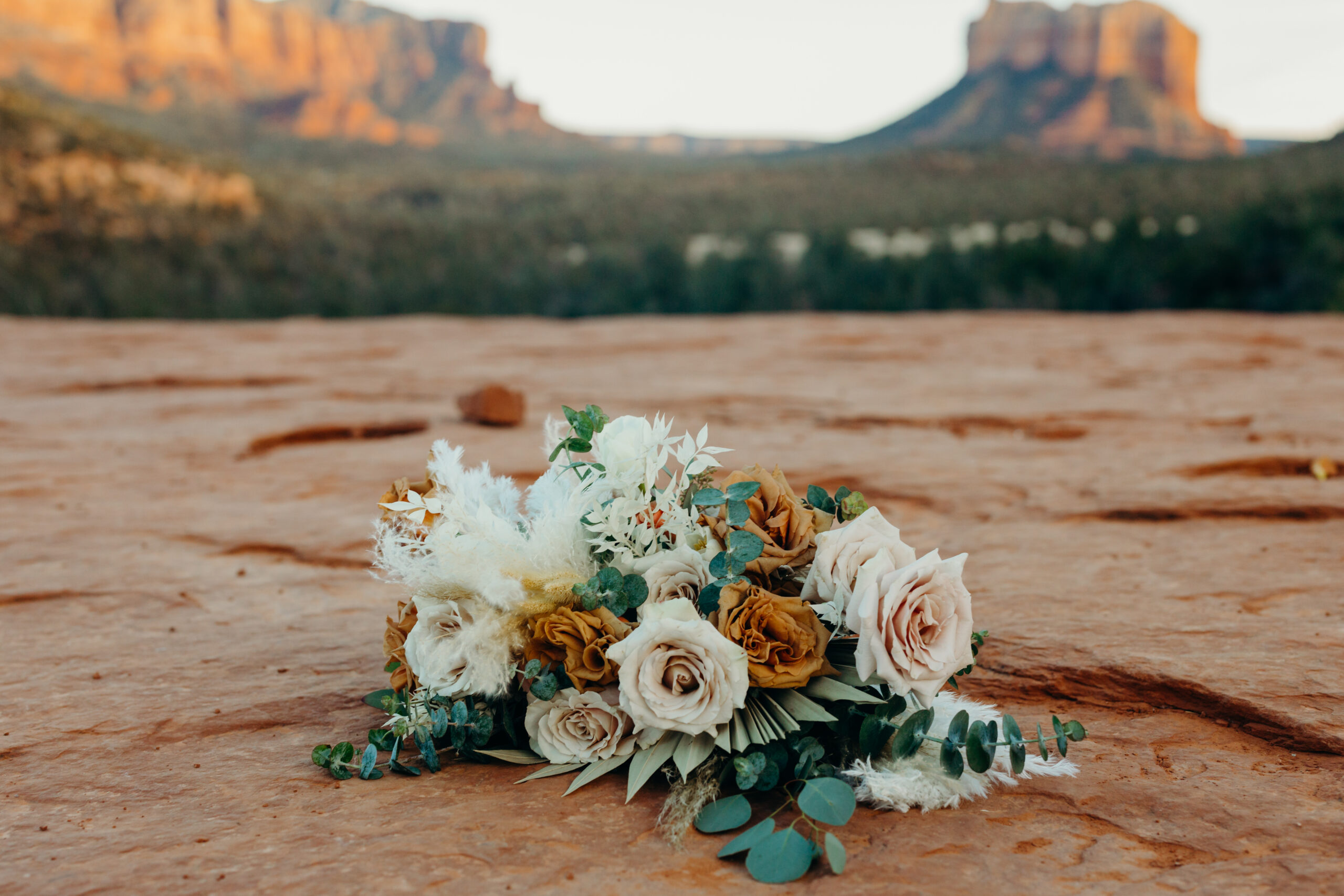 neutral toned wedding bouquet on red rock base of cathedral rock hike