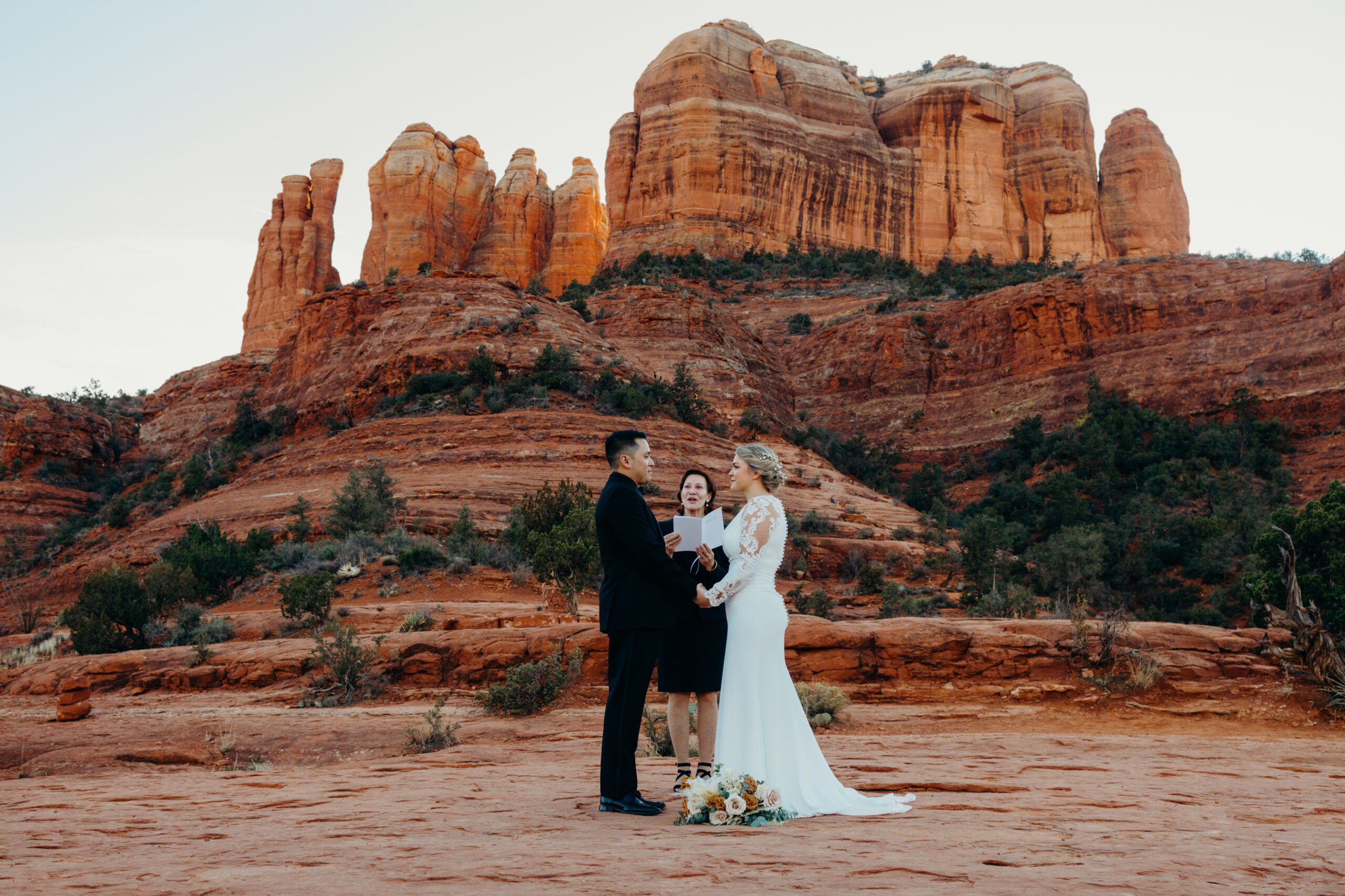 man and woman eloping on the base of cathedral rock with officiant in center